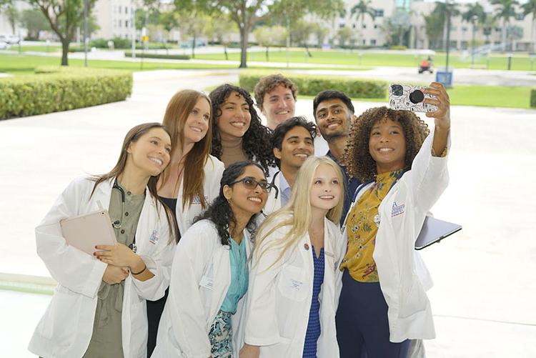 FAU medical students taking group selfie outside of the Schmidt College of Medicine building in Boca Raton, FL